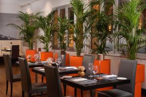 a dining room with tables and chairs and plants at NH Trieste in Trieste +37 photos