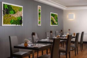 a dining room with long tables and chairs and paintings at NH Trieste in Trieste