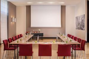 a conference room with a long table and red chairs at NH Trieste in Trieste