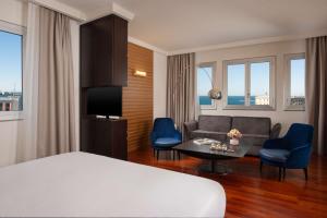 a hotel room with a bed and a couch and a table at NH Trieste in Trieste