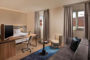 a hotel room with a desk and a bed at NH Trieste in Trieste