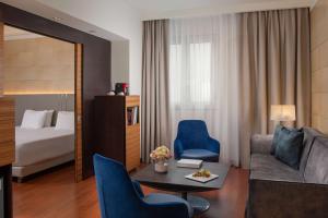 a hotel room with a bed and a living room at NH Trieste in Trieste
