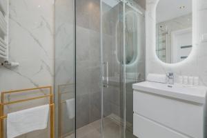 a bathroom with a glass shower and a sink at Nowoczesny Apartament w Gliwicach z Umeblowanym Balkonem by Noclegi Renters in Gliwice