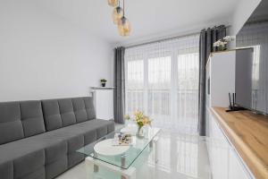 a living room with a couch and a glass table at Nowoczesny Apartament w Gliwicach z Umeblowanym Balkonem by Noclegi Renters in Gliwice