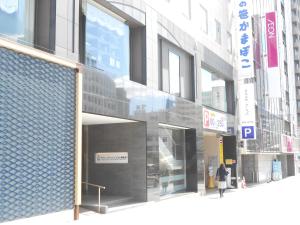a woman is walking in front of a building at Hotel Crown Hills Sendai Aobadori in Sendai