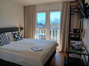 a bedroom with a bed with a view of a balcony at Hotel Fuchs & Hase SELF CHECK IN in Rosegg