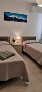een slaapkamer met twee bedden en een tafel met een lamp bij La Perla in Taormina
