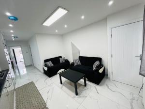 a living room with two black couches and a table at 93 New Road in Harmondsworth