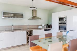 a kitchen with white cabinets and a glass table at Spacious T4 with Wifi on the seafront in Saint-Philibert