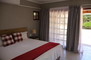 Un dormitorio con una cama y una ventana grande. en Boksburg Hotel, en Boksburg
