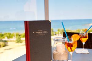 a book sitting on a table with two glasses of wine at Morada Strandhotel Ostseebad Kühlungsborn in Kühlungsborn