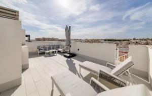 a patio with white chairs and tables on a roof at Luxury Penthouse - Rooftop Pool - 100m to the Sea in Torrevieja