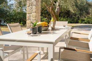 a white dining table and chairs on a patio at Olive Garden House in Gastourion