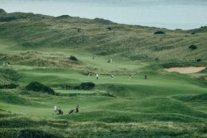 a group of people playing golf on a golf course at Portrush Adelphi in Portrush