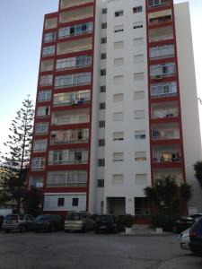 un edificio alto con coches estacionados frente a él en Beach and City Apartment, en Portimão