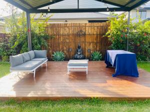 a patio with a couch and a table on a wooden deck at Mystic Garden Private Entry & Bath, Pet Friendly in Wentworthville