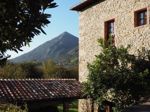 un edificio de piedra con una montaña en el fondo en Casa Rural La Roza 2, en Buelles