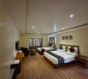 a hotel room with two beds and a desk at Hotel Glanton Manor in Ooty