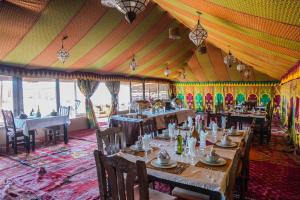 a dining room with tables and chairs in a tent at Riad Moha in Merzouga