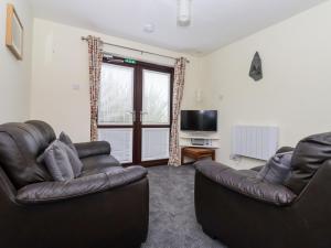 a living room with two leather couches and a television at Kenegie Cottage in Penzance