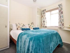 a bedroom with a bed with a blue blanket on it at Kenegie Cottage in Penzance +12 photos
