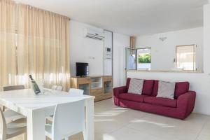 a living room with a white table and a red couch at Villa Cormorani 1 in Golfo Aranci