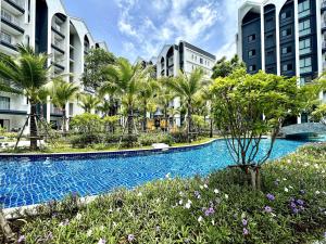 a swimming pool with palm trees and buildings at Halo the Title in Ban Nong Chaeng
