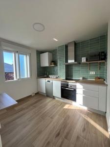 eine Küche mit weißen Schränken und einem Holzboden in der Unterkunft O Refuxio da Ría in Pontevedra