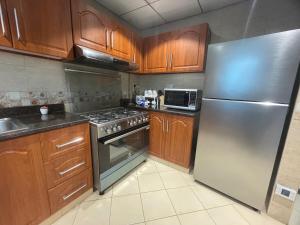 a kitchen with wooden cabinets and a stainless steel refrigerator at Beachfront gem, waves and sunset in Ajman  +9 photos