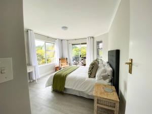 a white bedroom with a bed and windows at 34 Summerplace, Knysna in Knysna