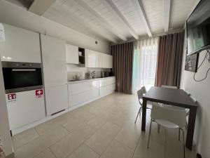 a kitchen with white cabinets and a table and chairs at De Luxe Apartments Eden in Sirmione
