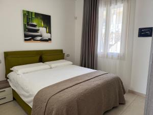 a bedroom with a bed with a green headboard and a window at De Luxe Apartments Eden in Sirmione