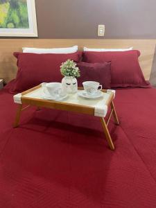 a table with two cups and plates on a bed at Aldeia das Águas Village Park Flat A110 térreo in Barra do Piraí