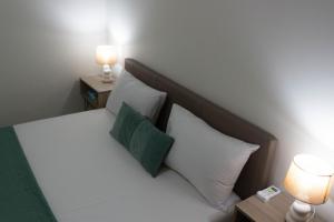 a bed with two white pillows and two lamps at Golden sand apartment B in Hersonissos