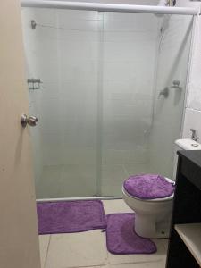 a bathroom with a shower and a toilet with purple mats at Aldeia das Águas Village Park Flat A110 térreo in Barra do Piraí