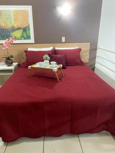a bedroom with a red bed with a table on it at Aldeia das Águas Village Park Flat A110 térreo in Barra do Piraí