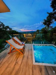 a chair sitting on a deck next to a swimming pool at Vivenda Apua Chalés in Piracaia