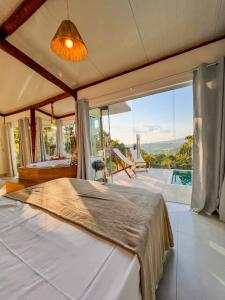 a bedroom with a large bed and a large window at Vivenda Apua Chalés in Piracaia