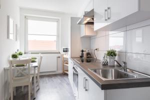 a white kitchen with a sink and a table at Apart2Stay in Düsseldorf
