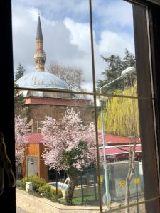 a window view of a mosque with a tree at Utopia Konak Otel in Bozuyuk