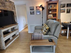a living room with a couch and a television at Sied Yr Ardd in Ystradgynlais