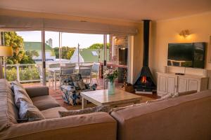 a living room with a couch and a table with a fireplace at The Mountainview Family Retreat in Hermanus