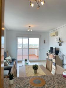 a living room with a dining room table and a kitchen at Apartamento 3 habitaciones en la playa de Magic World , Oropesa del Mar in Cabanes