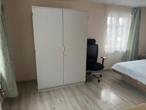 een slaapkamer met een witte kast en een bed en een stoel bij Small house in Vilnius +1 foto
