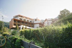 a building on top of a hill with bushes at Boutique Hotel Pachers in Bressanone