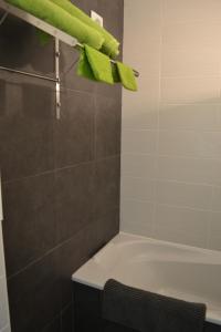 La salle de bains est pourvue d'une baignoire et d'une serviette verte. dans l'établissement Studio 24 Oostende, à Ostende