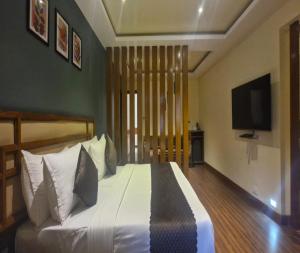 a bedroom with a large white bed with a flat screen tv at Hotel Glanton Manor in Ooty