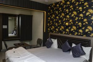 UlhāsnagarHotel Grace Lodging & Boarding的卧室配有一张大床,墙上挂着花卉图案