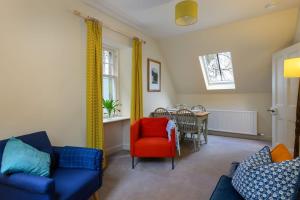 a living room with blue and red chairs and a table at The Stable Flat - 20 minutes from St Andrews in Cupar