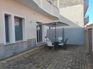 a patio with a table and chairs and an umbrella at Bach Room 73 in Porto Cesareo